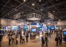 Wide view of an exhibition hall filled with visitors and stands